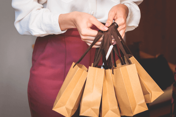 An image of a female holding 5 brown gift bags.