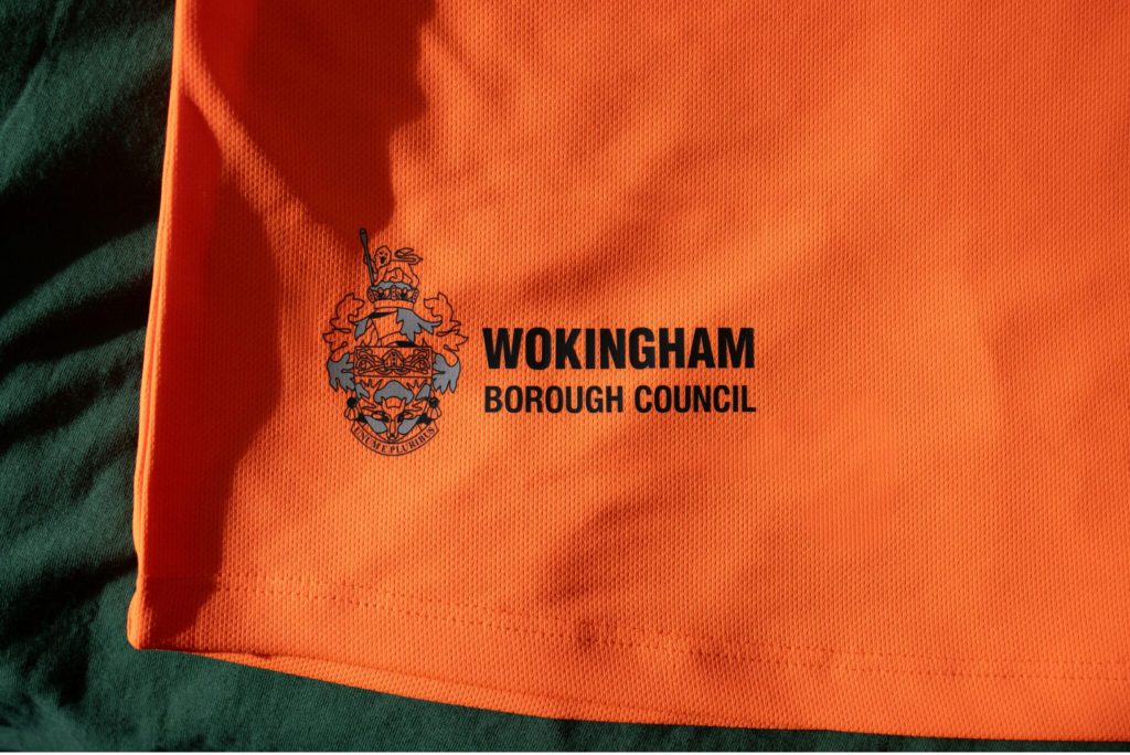 The bottom right hem of an orange hi-vis t-shirt featuring Wokingham Borough Council's logo.